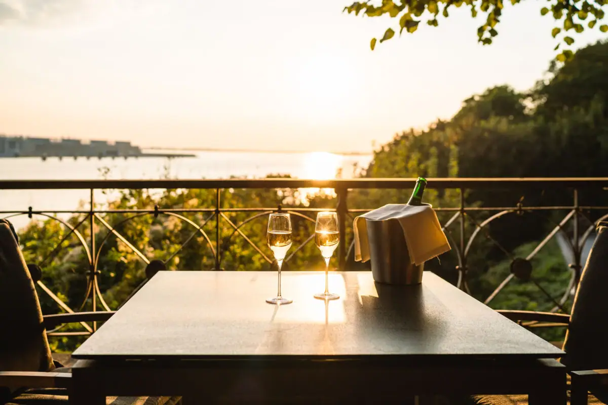 Zwei Champagnergläser stehen auf einem Tisch mit Flussblick 