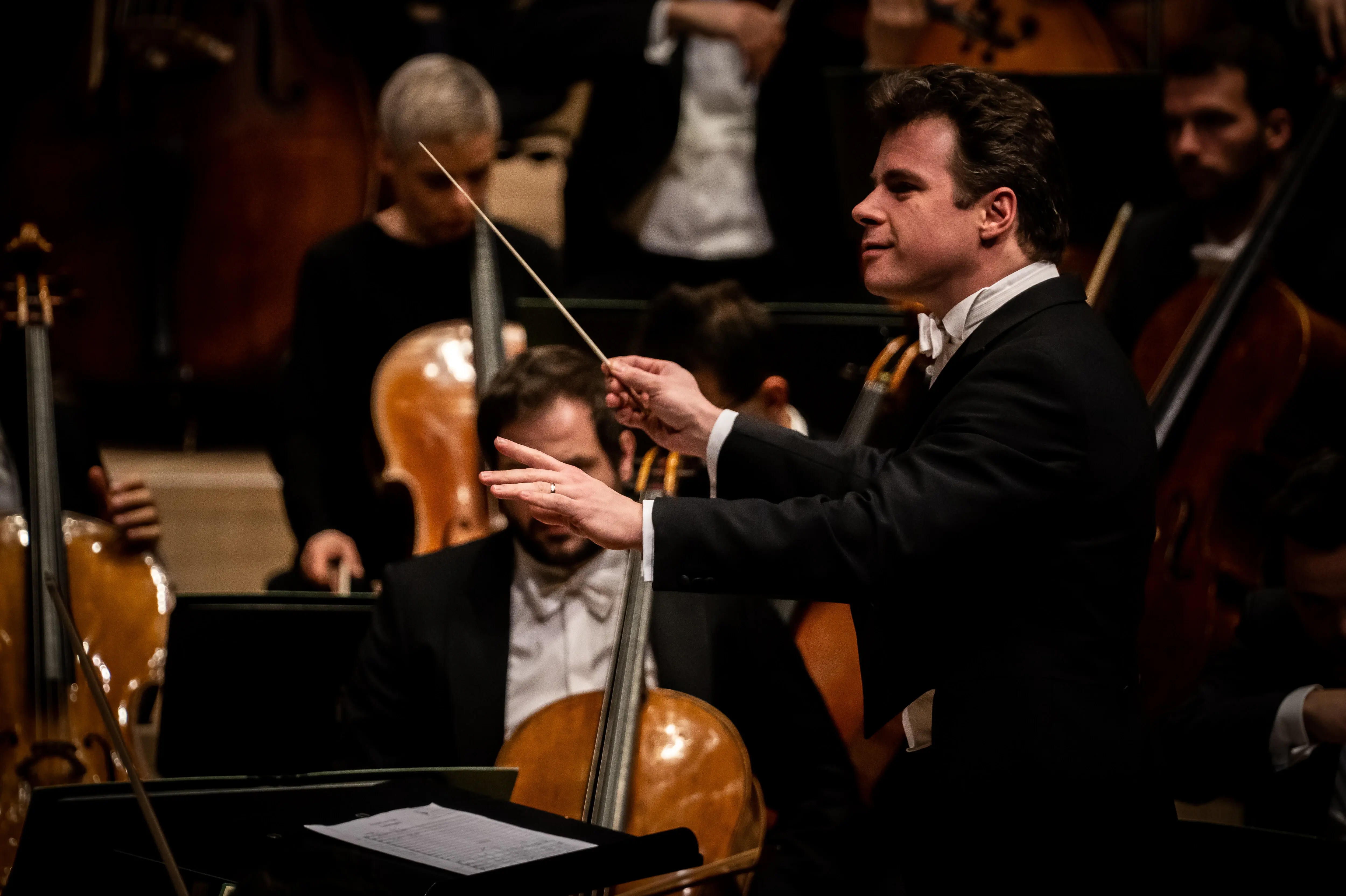 Ein Mann dirigiert ein Orchester mit Streichinstrumenten.
