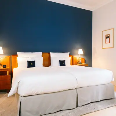 Bett in einem Zimmer mit dunkelblauer Wand im Hotel Louis C. Jacob.