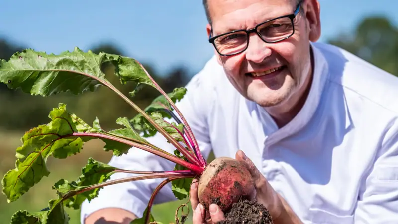 Der Koch Thomas Martin hält eine frische Rübe in der Hand.