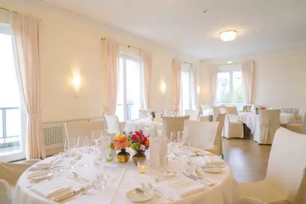 Veranstaltungsraum im Hotel Louis C. Jacob mit runden Tischen, die für eine private Feier eingedeckt sind.