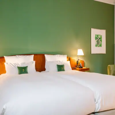 Ein Bett mit weißen Laken und Kissen in einem Zimmer mit grünen Wänden.