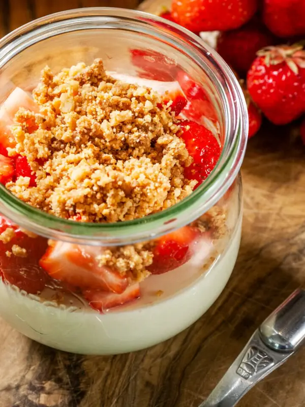 Ein Glas Dessert mit Erdbeeren und einem Löffel.