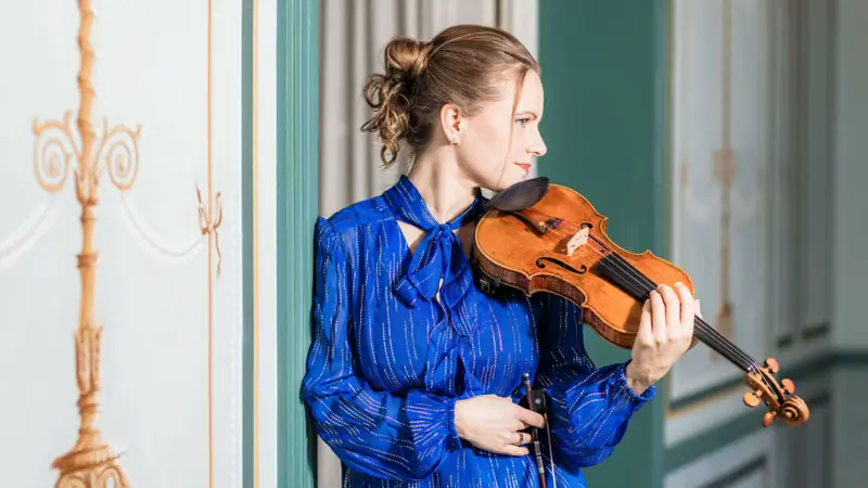 Julia Fischer Eine Frau hält eine Violine.