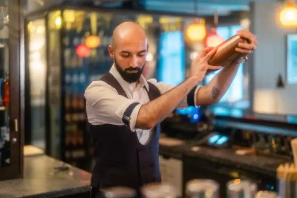 Barkeeper mixt einen Cocktail in einem Shaker in der Luft.