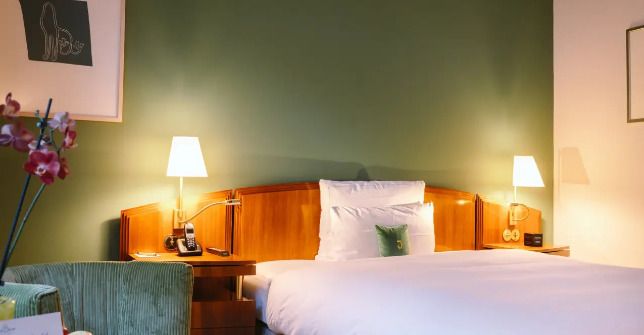 Ein Bett mit Holzkopfteil und Lampen in einem stilvoll eingerichteten Einzelzimmer. im Hotel Louis C. Jacob in Hamburg.