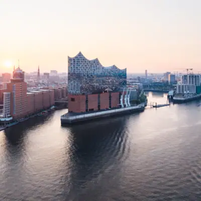 Stadt mit Fluss und Gebäuden, im Vordergrund ein Schiff auf dem Wasser.