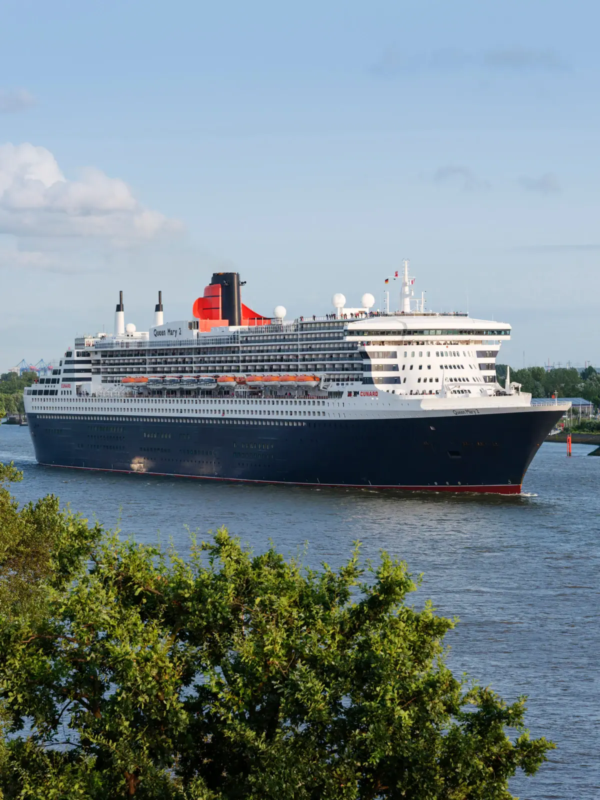 Ein großes Schiff im Wasser mit der RMS Queen Mary im Hintergrund.