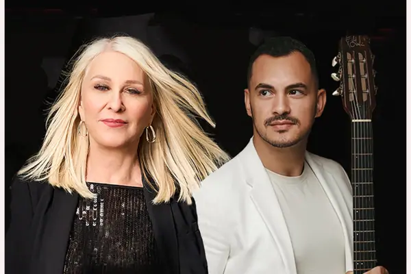 Ein Mann und eine Frau posieren lächelnd für ein Foto mit einer Gitarre.